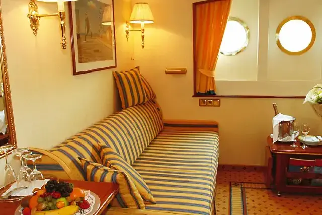 Каюта на главной палубе категории Lux:
-Три иллюминатора (не открываются);
-Одна двуспальная кровать или две односпальные;
-Индивидуальный кондиционер;
-Ванная комната с душем;
-Фен;
-Спутниковое телевидение;
-Сейф;
-Телефон..webp